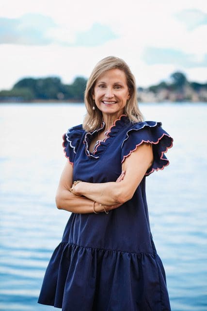 Smiling woman standing by a lake.