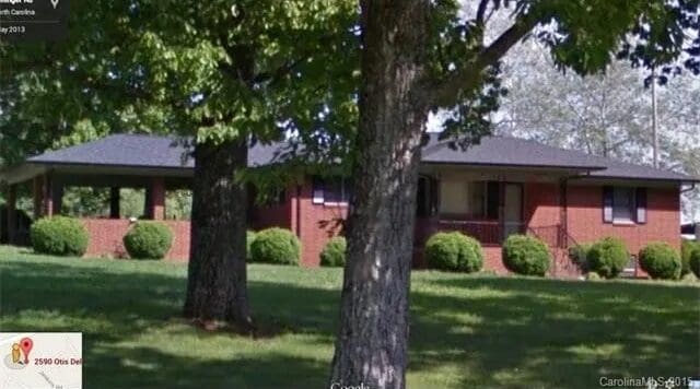 Brick house with trees and bushes outside.