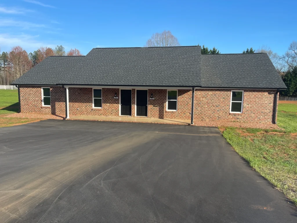 Brick duplex with asphalt driveway and lawn