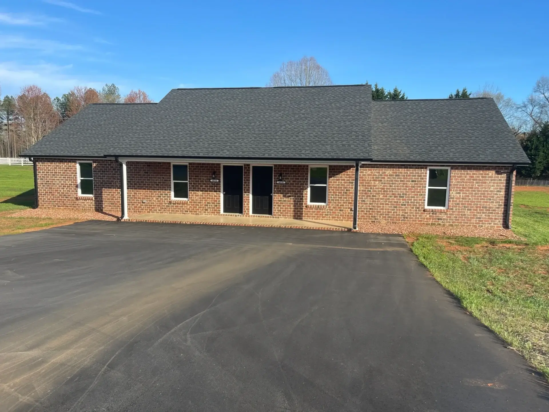 Brick duplex with asphalt driveway and lawn