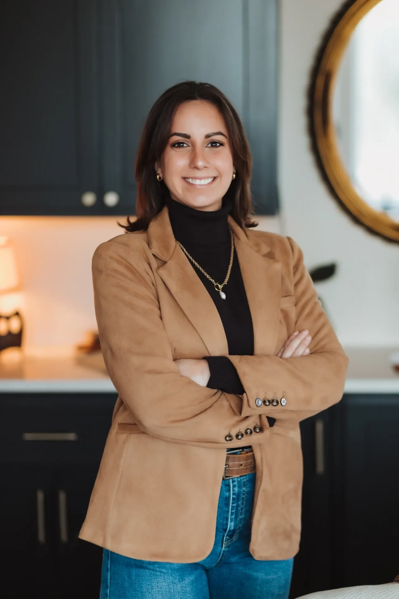 Smiling woman in tan blazer with arms crossed