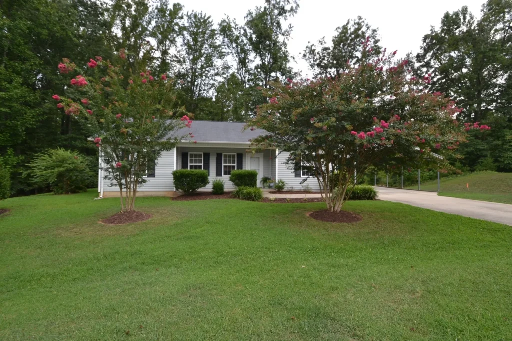 Small house with blooming trees and lawn.
